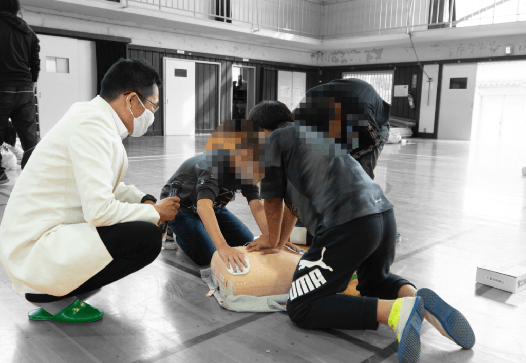 小学校でAEDの使い方を指導する内野勝行医師